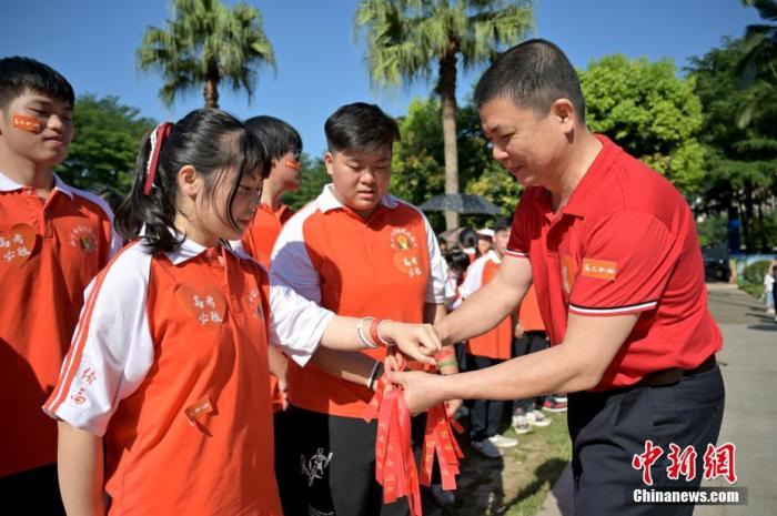 資料圖：廣西華僑實驗高中的教師為高三學(xué)子系上紅絲帶，盼望學(xué)子高考必勝。 俞靖 攝